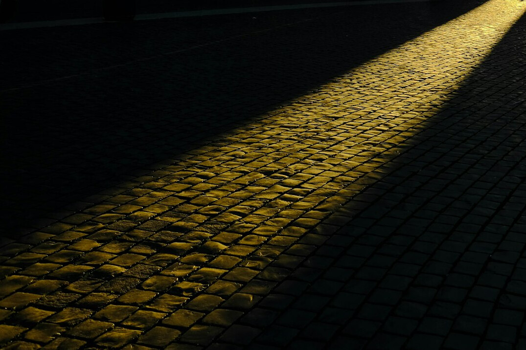 Empty cobblestone street at night under streetlight